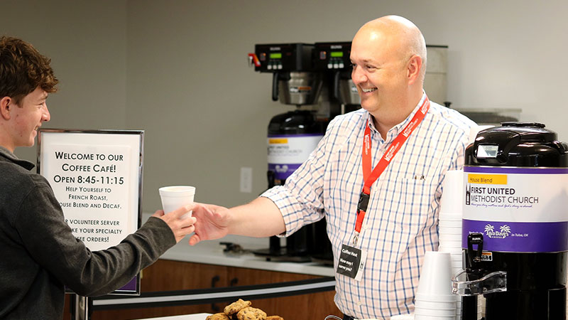 Man giving another person a cup of coffee